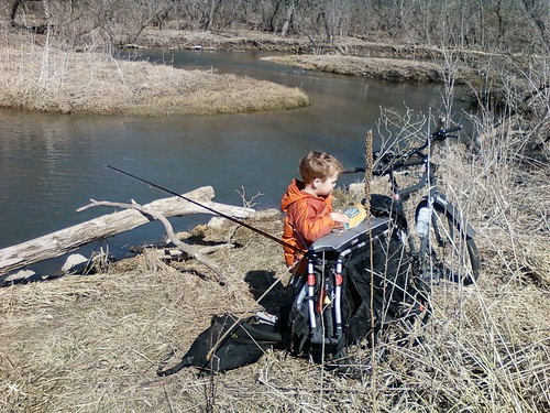 Rear, right side view of a Surly Big Dummy bike with a child on the left side, parked on a bank above a stream