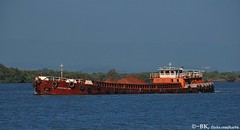A boat carrying iron ore from a ship to the fa...