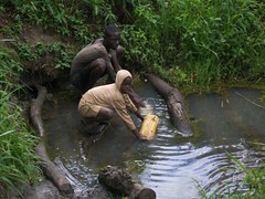 Two boys collect water at the open source