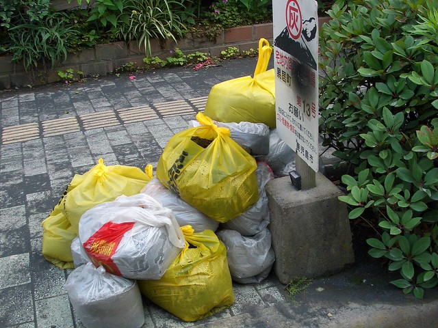 桜島の噴火でたまった灰を、専用のごみ袋に集めて捨てるとのこ。｜桜島港