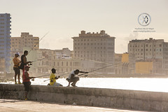 Men fish at sunset on Havana's Malecon boardwalk.