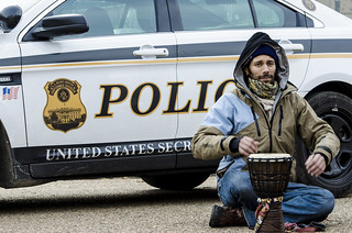 Abe Velazquez Plays a Drum Near a Police Car